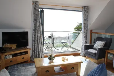 a living room with a tv and a large window at Seascape - Mount Brioni in Downderry