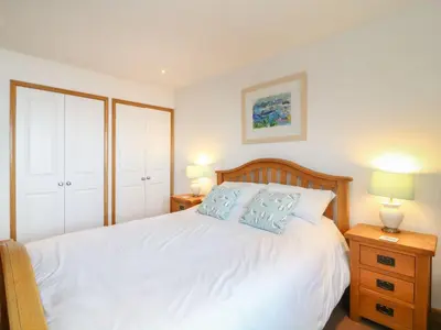 a bedroom with a white bed with blue pillows at Seascape - Mount Brioni in Downderry