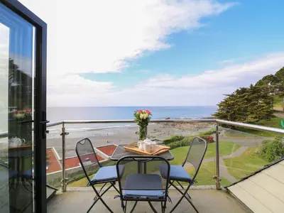 a table and chairs on a balcony with a view of the ocean at Seascape - Mount Brioni in Downderry