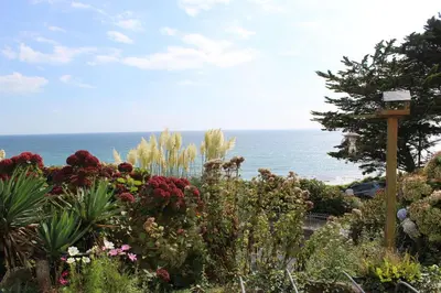 a garden with flowers and the ocean in the background at Seascape - Mount Brioni in Downderry