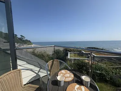 a balcony with a table and chairs and the ocean at Lowena - Mount Brioni in Downderry