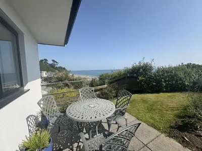 a patio with a table and chairs and the ocean at Lowena - Mount Brioni in Downderry