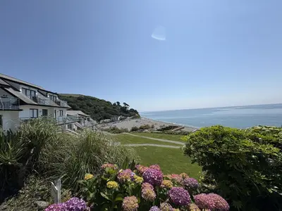 a view of the ocean from a house with flowers at Lowena - Mount Brioni in Downderry