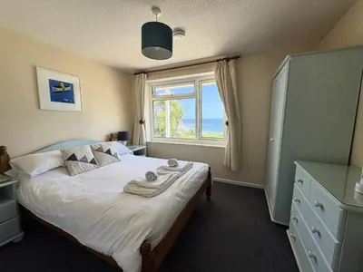 a bedroom with a large bed with a window at Surf Watch - Mount Brioni in Downderry