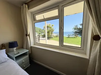 a bedroom with a window with a view of the ocean at Surf Watch - Mount Brioni in Downderry