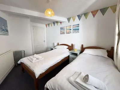 two beds in a small room with flags on the wall at Surf Watch - Mount Brioni in Downderry