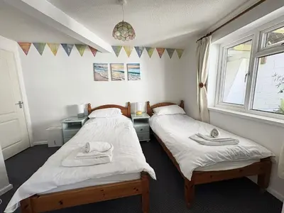 two beds in a room with two windows at Surf Watch - Mount Brioni in Downderry