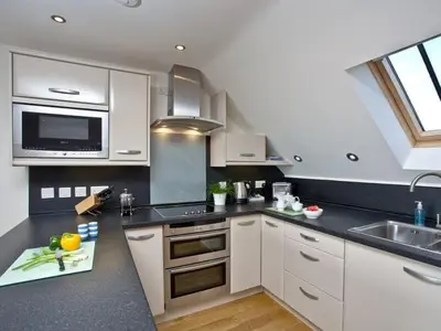 a kitchen with white cabinets and a sink at Eddystone View - Mount Brioni in Downderry