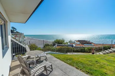 a patio with a table and chairs and the ocean at Eddystone View - Mount Brioni in Downderry
