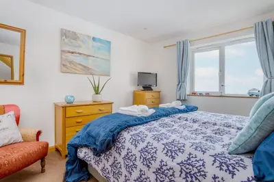a bedroom with a blue and white bed and a window at Eddystone View - Mount Brioni in Downderry