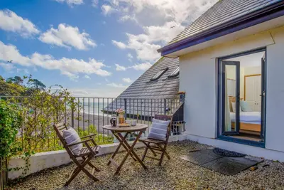 a table and chairs on the balcony of a house at Eddystone View - Mount Brioni in Downderry