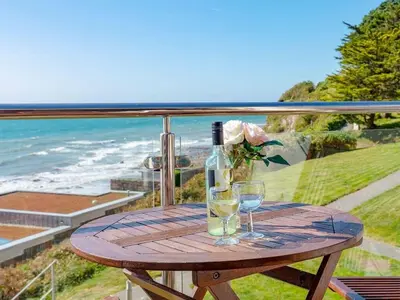 a wooden table with two glasses and a bottle of wine at Eddystone View - Mount Brioni in Downderry
