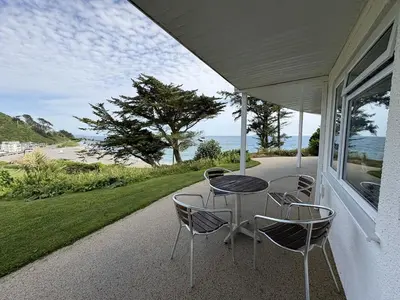 a table and chairs on the porch of a house at Cornish Riviera - Mount Brioni in Downderry