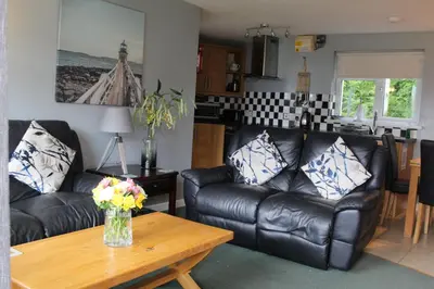 a living room with two black leather couches and a table at Cornish Riviera - Mount Brioni in Downderry