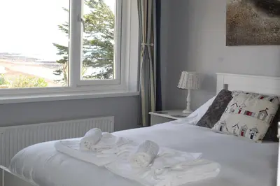 a bedroom with a white bed with towels on it at Salty Air - Mount Brioni in Downderry