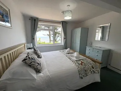 a bedroom with a large white bed with a window at Sea Breeze - Mount Brioni in Downderry