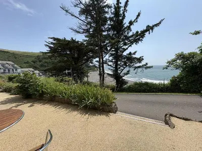 a road with a tree and a beach and the ocean at Sea Breeze - Mount Brioni in Downderry