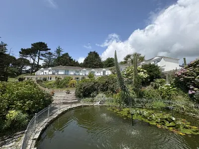 a pond in a garden with a house in the background at Sea Breeze - Mount Brioni in Downderry