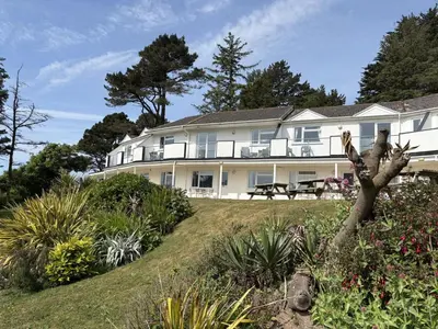 a large white house with a garden in front of it at Sea Breeze - Mount Brioni in Downderry