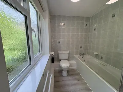 a bathroom with a toilet and a tub and a window at Sea Breeze - Mount Brioni in Downderry