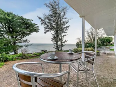 a table and chairs with a view of the ocean at Sand Bar - Mount Brioni in Downderry