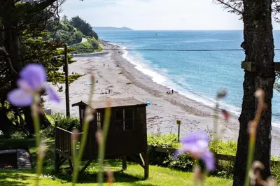 a view of a beach with purple flowers in the grass at Sand Bar - Mount Brioni in Downderry