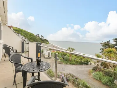 a balcony with a table and a view of the ocean at Tide Watch - Mount Brioni in Downderry