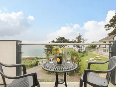 a table with a bottle of wine on a balcony at Tide Watch - Mount Brioni in Downderry