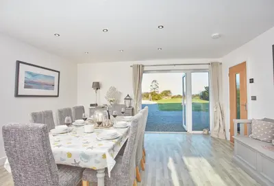 a white dining room with a table and chairs at Treveth Lowen in Saint Minver