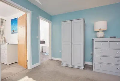 a bedroom with blue walls and a white closet at Treveth Lowen in Saint Minver