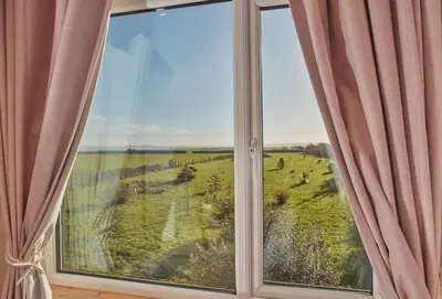 a window with a view of a green field at Treveth Lowen in Saint Minver