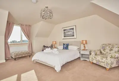 a bedroom with a bed and a couch and a chair at Treveth Lowen in Saint Minver