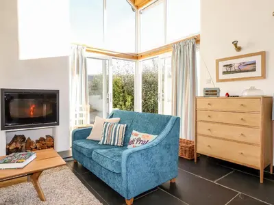 a living room with a blue couch and a tv at Jonwyns in Tintagel
