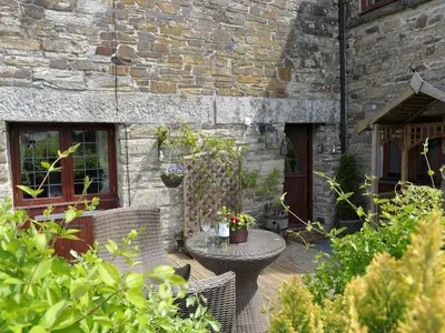 a patio with a table and chairs in front of a building at Nightingale Cottage in Liskeard