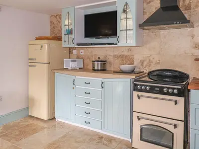 a kitchen with a stove and a refrigerator at Nightingale Cottage in Liskeard