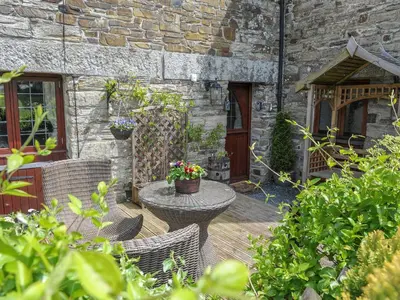 a patio with a table and chairs and a building at Nightingale Cottage in Liskeard