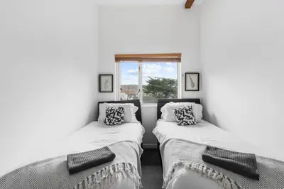two twin beds in a room with a window at Coppercroft Cottage - Stunning Coastal Home, Walk to Beach, Sleeps 4 in Porthtowan