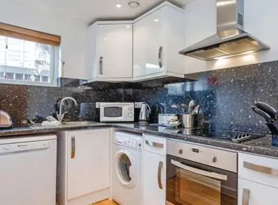 a kitchen with white cabinets and a stove top oven at Coppercroft Cottage - Stunning Coastal Home, Walk to Beach, Sleeps 4 in Porthtowan