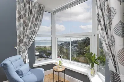 a living room with a blue chair and a large window at Windsor Lookout in St Ives