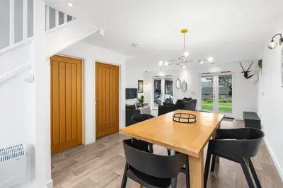 a dining room and living room with a wooden table and chairs at Silvercroft Cottage - Luxury Modern Coastal Retreat Near Beach, Sleeps 4 in Porthtowan