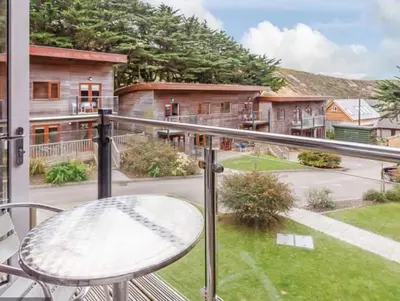 a balcony with a table and a view of a yard at Silvercroft Cottage - Luxury Modern Coastal Retreat Near Beach, Sleeps 4 in Porthtowan