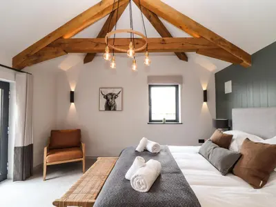 a bedroom with a large white bed and a chair at The Granary at Boskensoe Barns in Falmouth