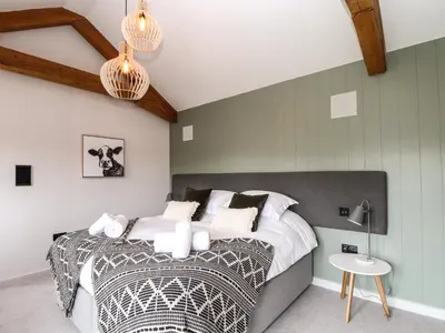a bedroom with a large bed and a table at The Granary at Boskensoe Barns in Falmouth