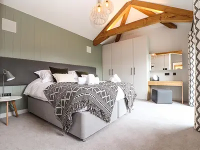 a bedroom with a large bed with a gray comforter at The Granary at Boskensoe Barns in Falmouth