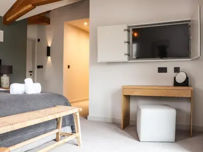a bedroom with a bed and a tv on the wall at The Granary at Boskensoe Barns in Falmouth