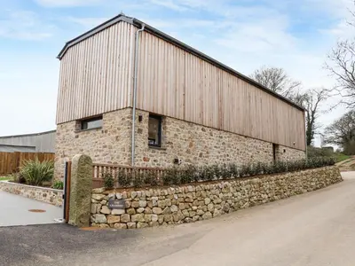 a large brick building with a stone wall at The Granary at Boskensoe Barns in Falmouth