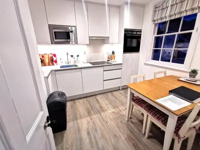 a kitchen with white cabinets and a wooden table at Malahne Apartment Port Isaac in Port Isaac