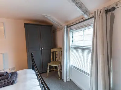 a bedroom with a bed and a window with a chair at Finest Retreats - Old Harbour Cottage in Mevagissey