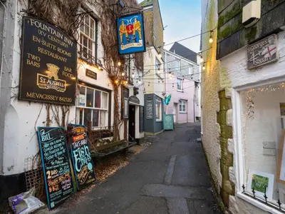 an alley with signs on the side of a building at Finest Retreats - Old Harbour Cottage in Mevagissey