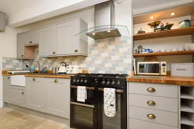 a kitchen with white cabinets and a black stove at Superb House in Looe, Near Beach and Bars with Great Views and free access to a nearby Indoor Swimming Pool in Looe